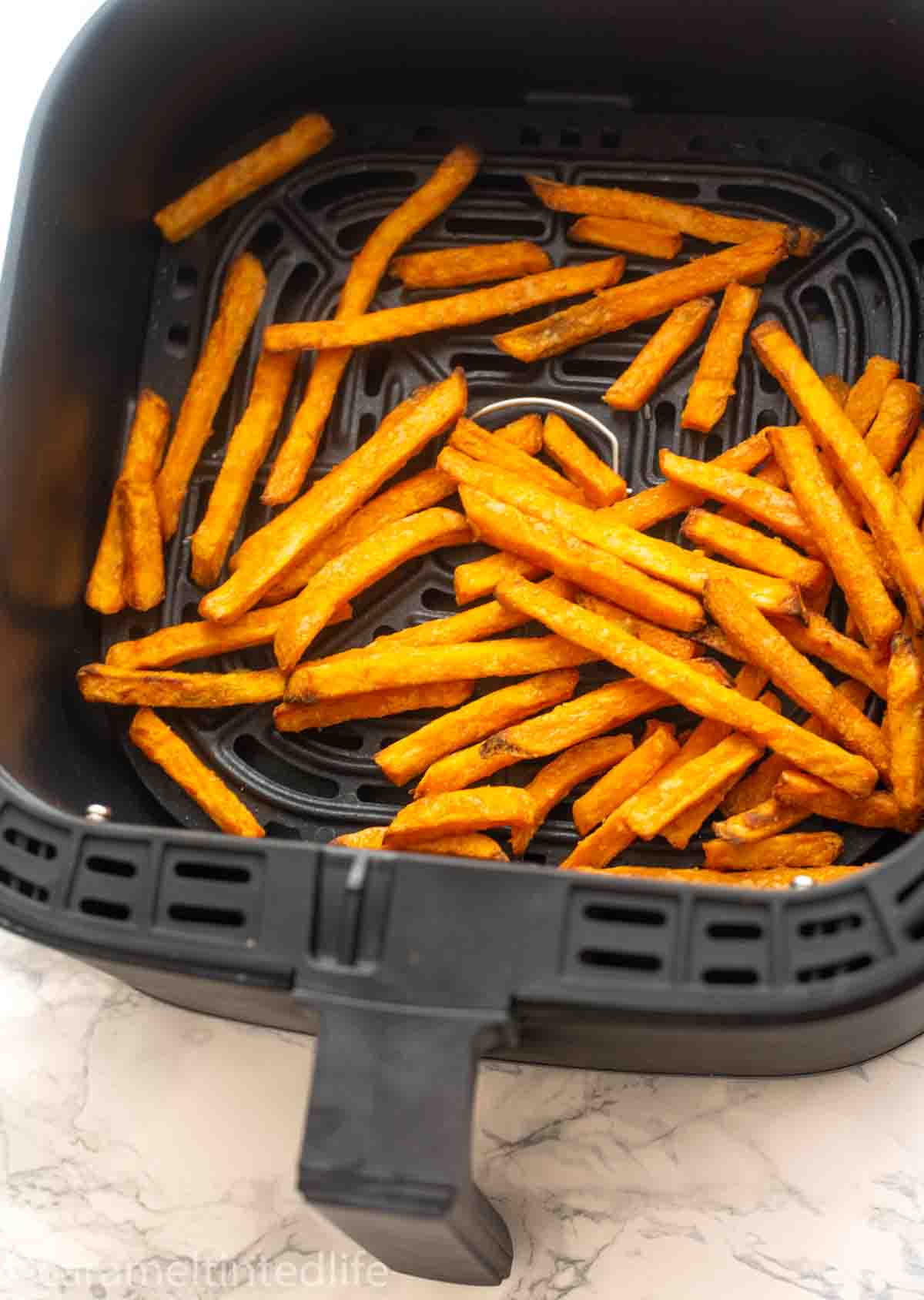 air fried sweet potato fries in an air fryer basket