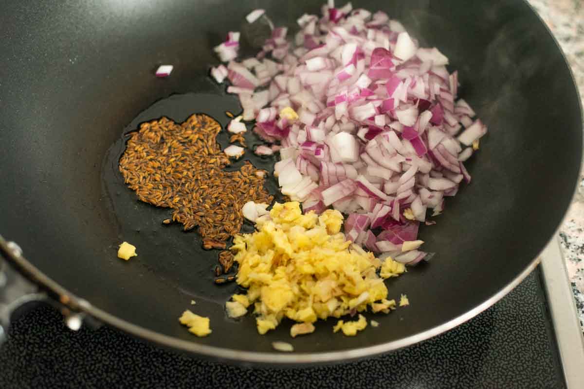 cumin, ginger garlic and onion frying in oil in a wok