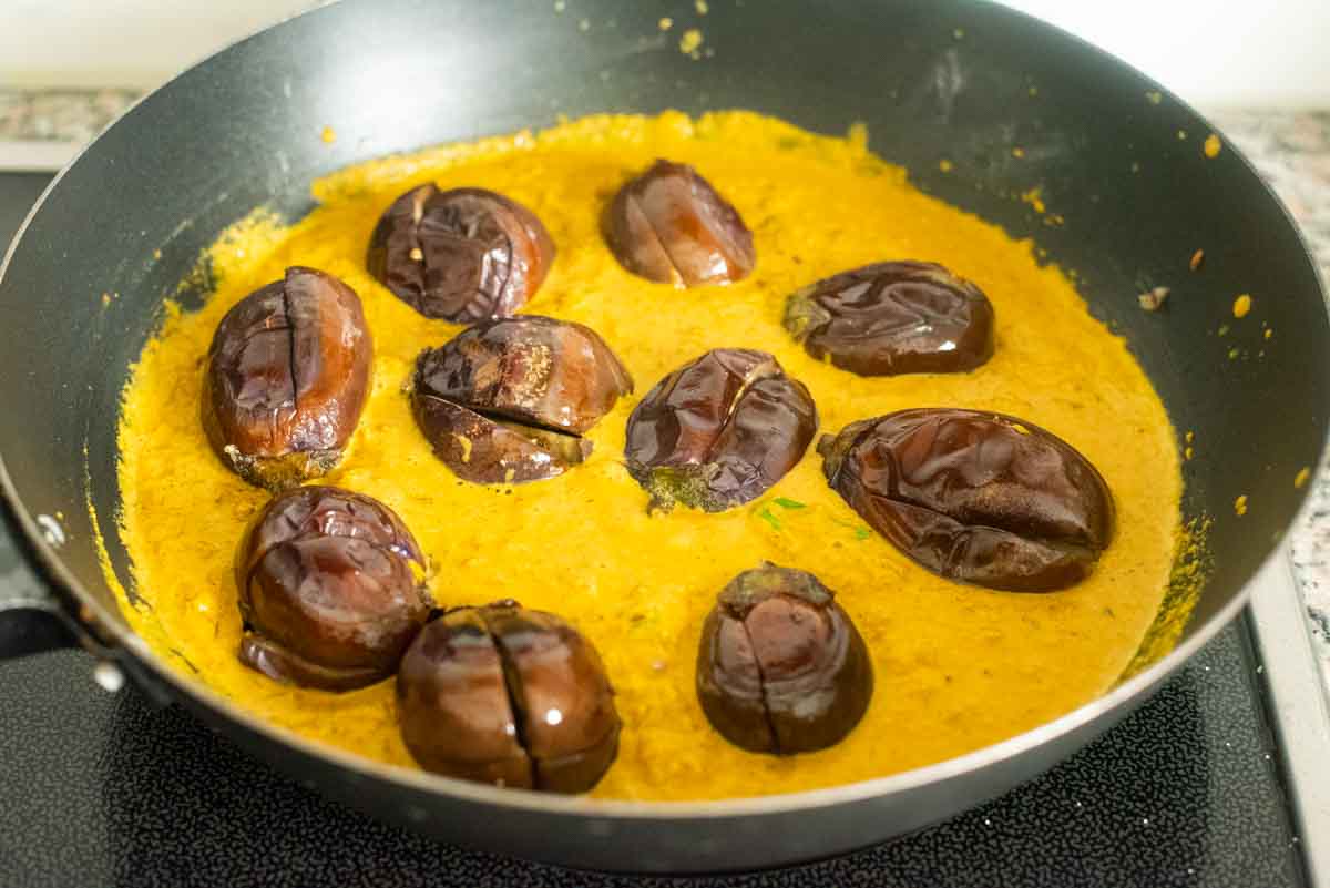 baby brinjal simmered in a curry in a wok