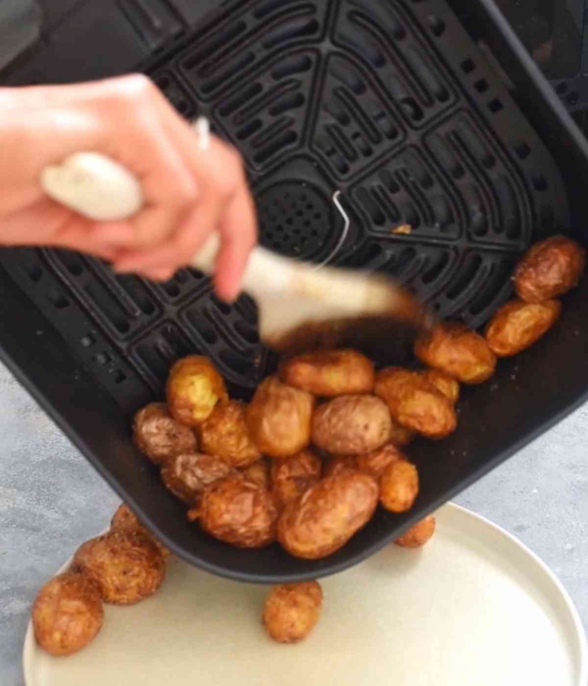 Roasted baby potatoes being transferred to a plate
