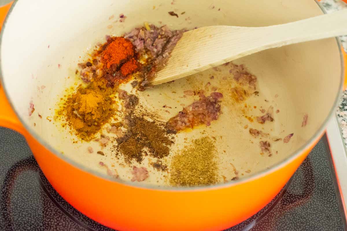 dutch oven with spices being heated on a stovetop