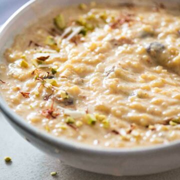 close up of a bowl of rice kheer with saffron and nut garnish