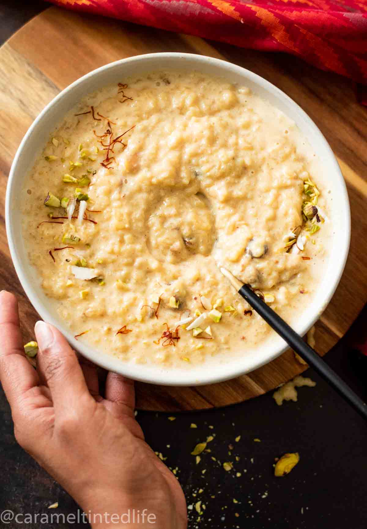 hand holding a bowl of rice kheer with a spoon