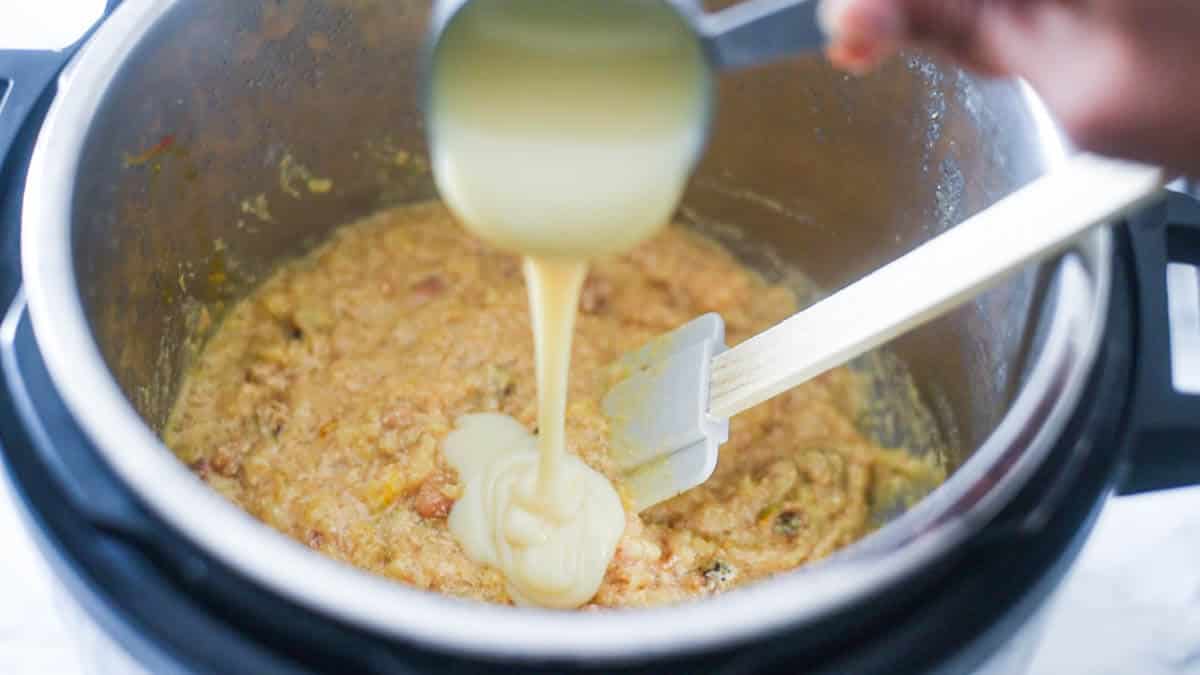 condensed milk being poured into a Instant Pot containing rice pudding