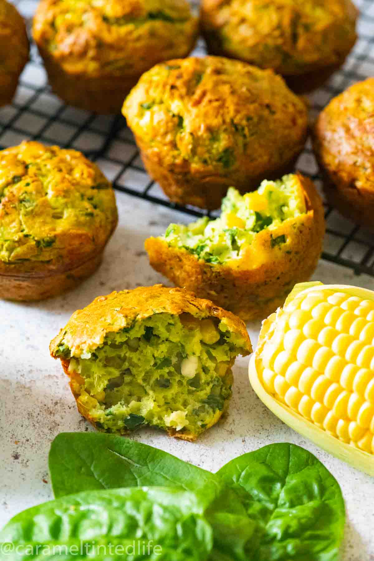 a broken spinach muffin with a corn cob and spinach leaves