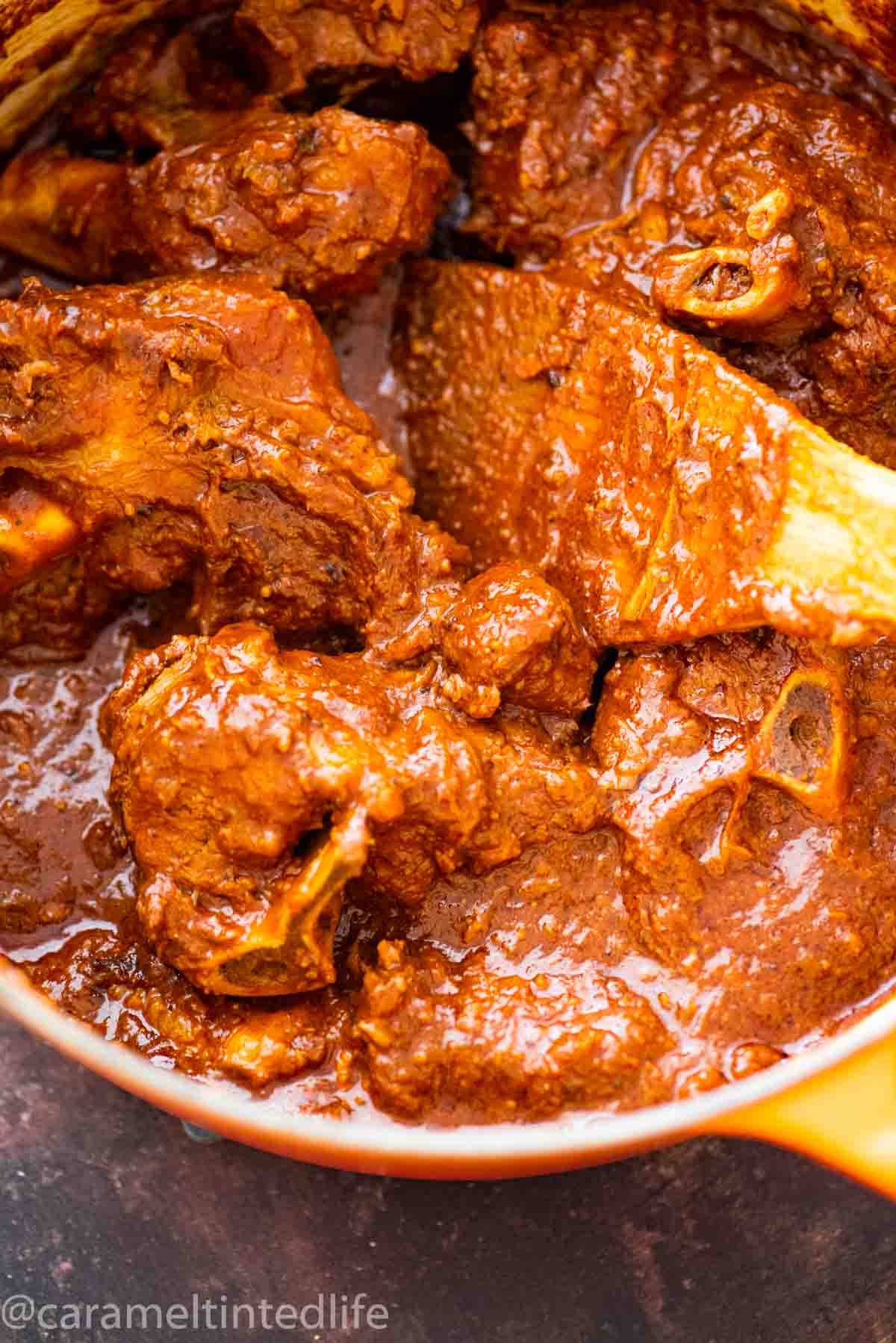 lamb curry in a dutch oven with a wooden spatula