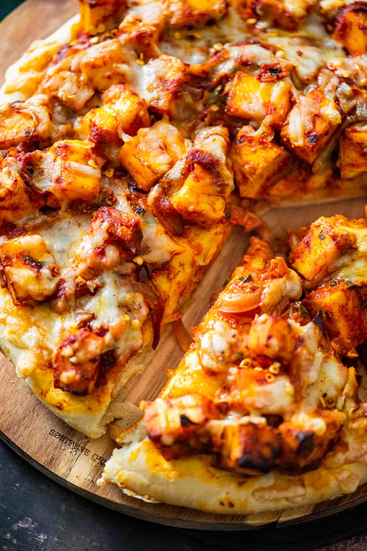 sliced paneer pizza on a wooden board