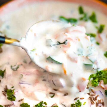 bowl of raita with spoon dipping into it