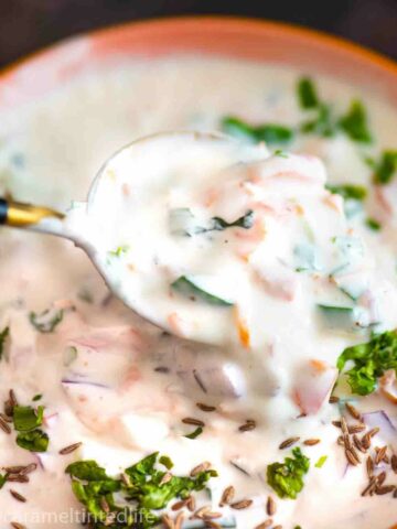 bowl of raita with spoon dipping into it