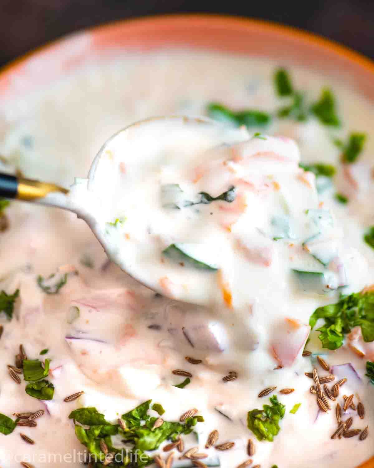 bowl of raita with spoon dipping into it