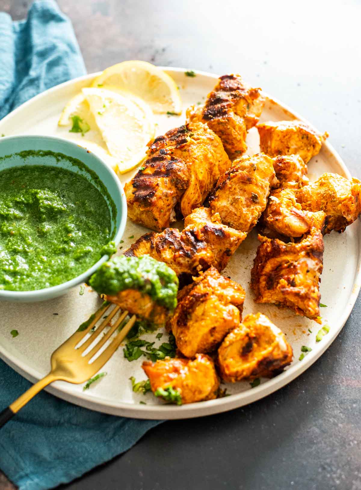 plate with pieces of tandoori chicken tikka with green chutney dip