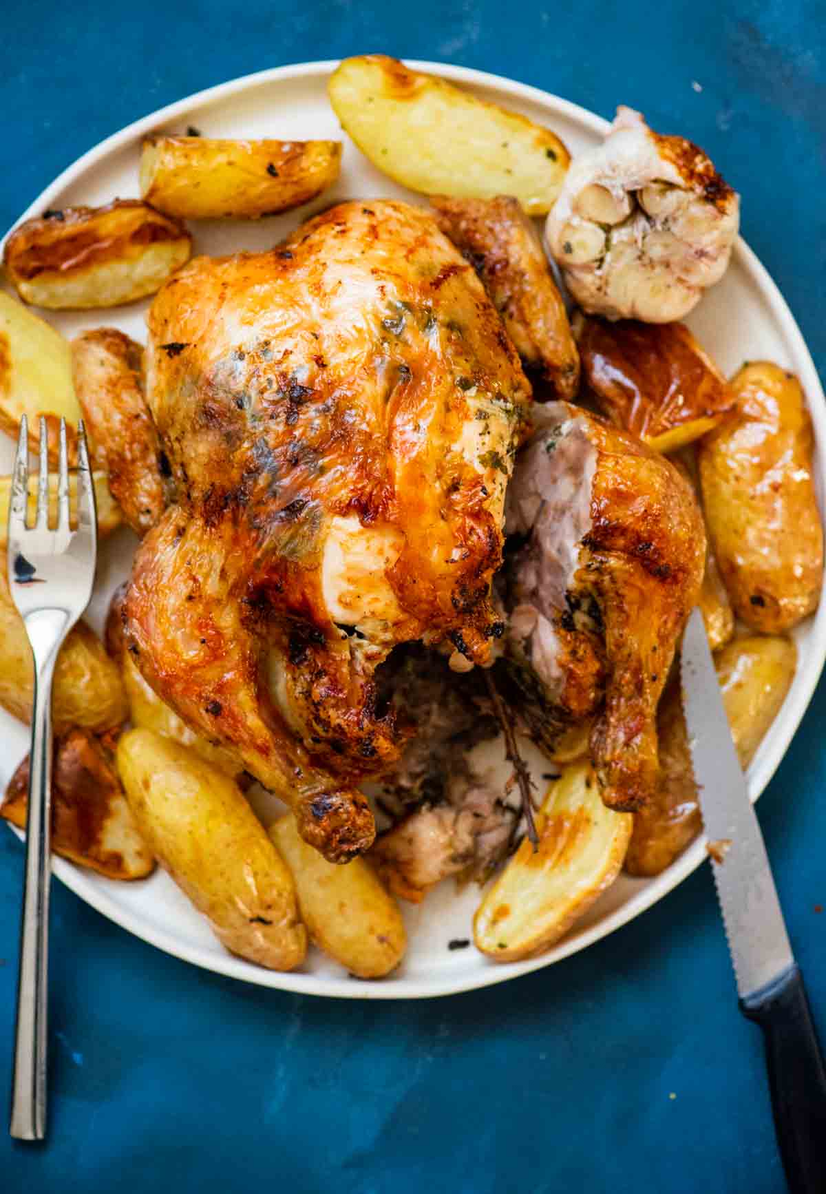 whole roasted chicken cut with knife and fork served with potatoes 