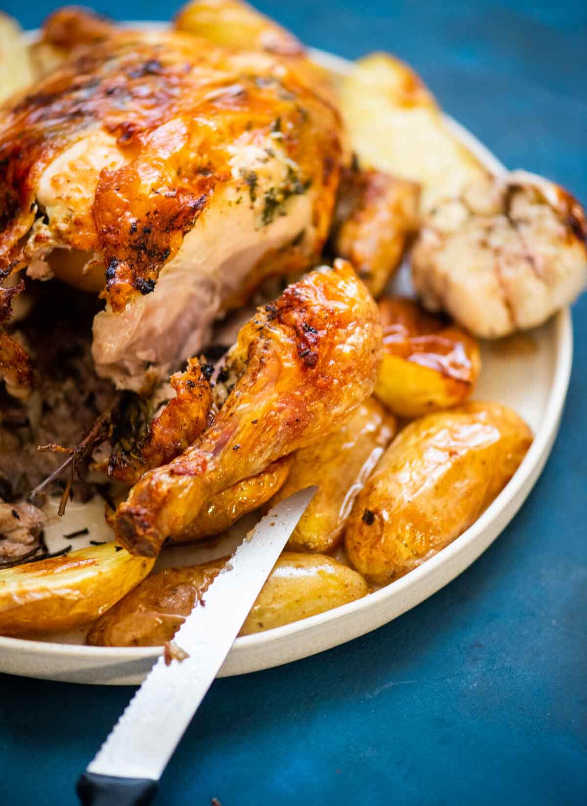 roast chicken sliced with fork next to roast potatoes