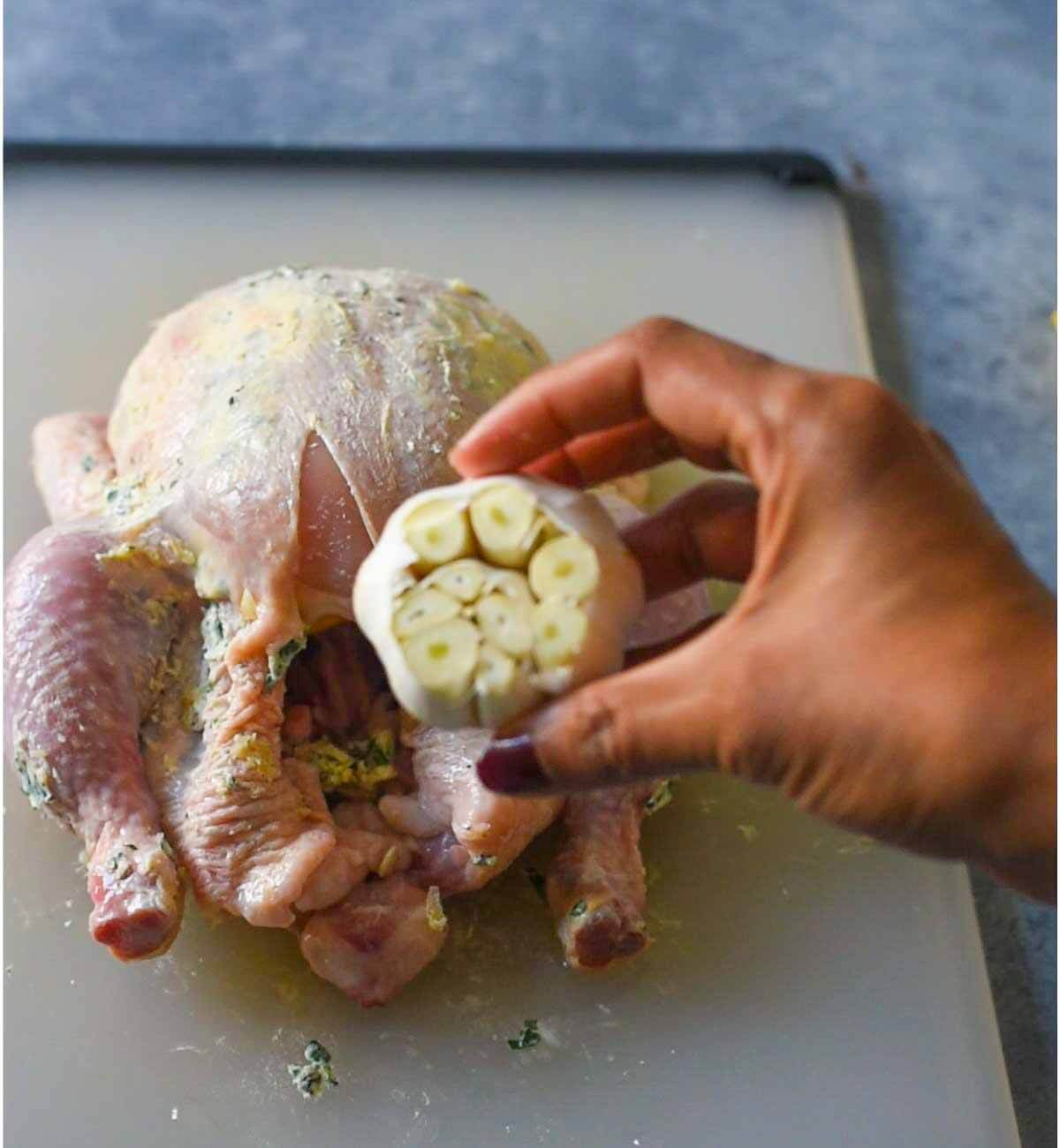 whole head of garlic in foreground of whole chicken