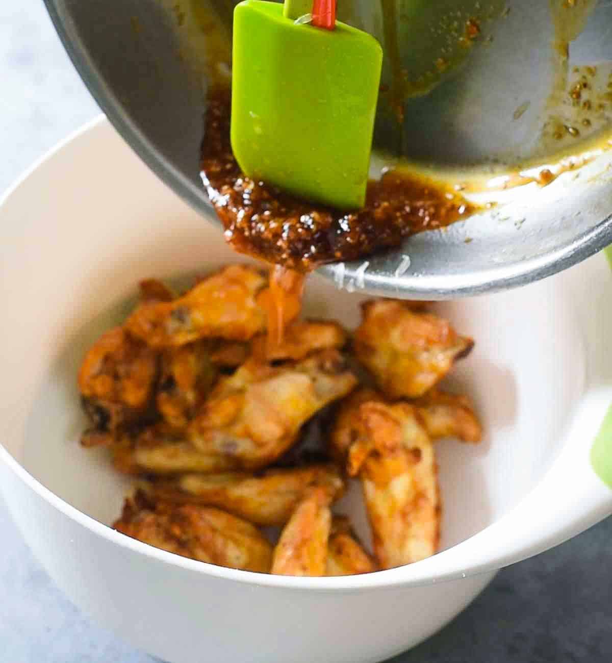 pouring sauces over chicken wings