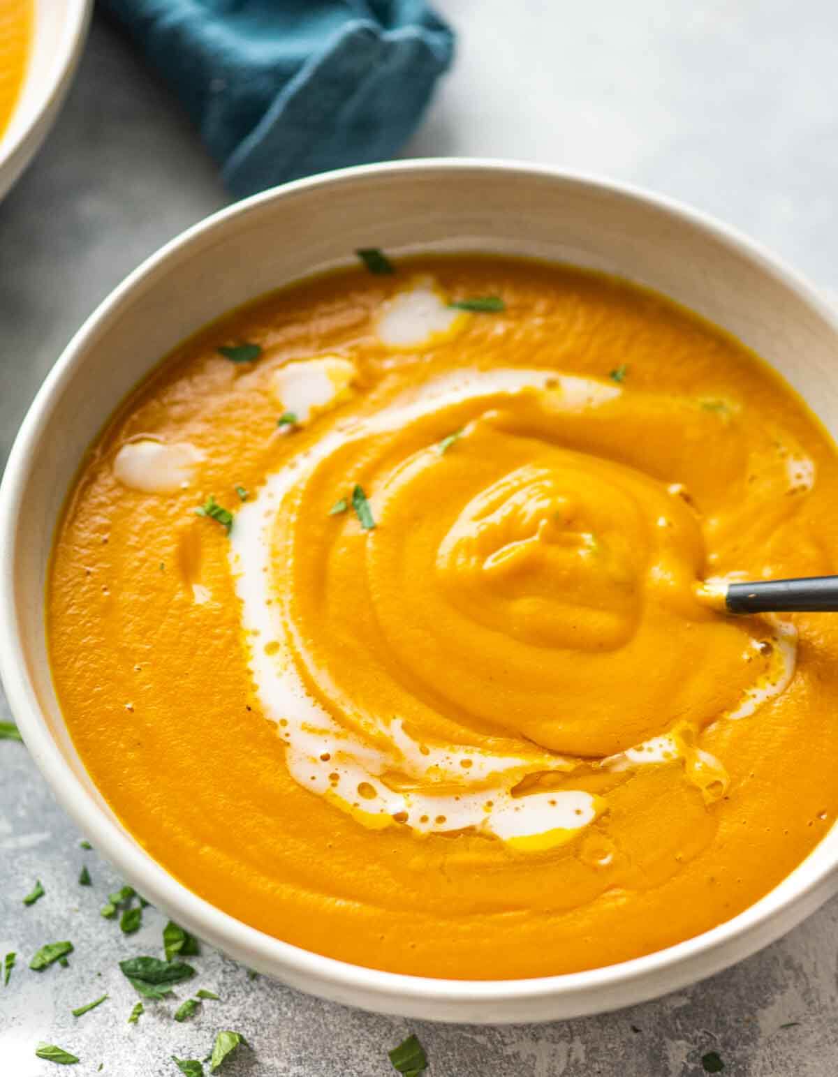 bowl of pumpkin soup with cream and parsley garnish