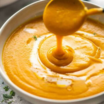 soup spoon pouring out pumpkin soup in a bowl