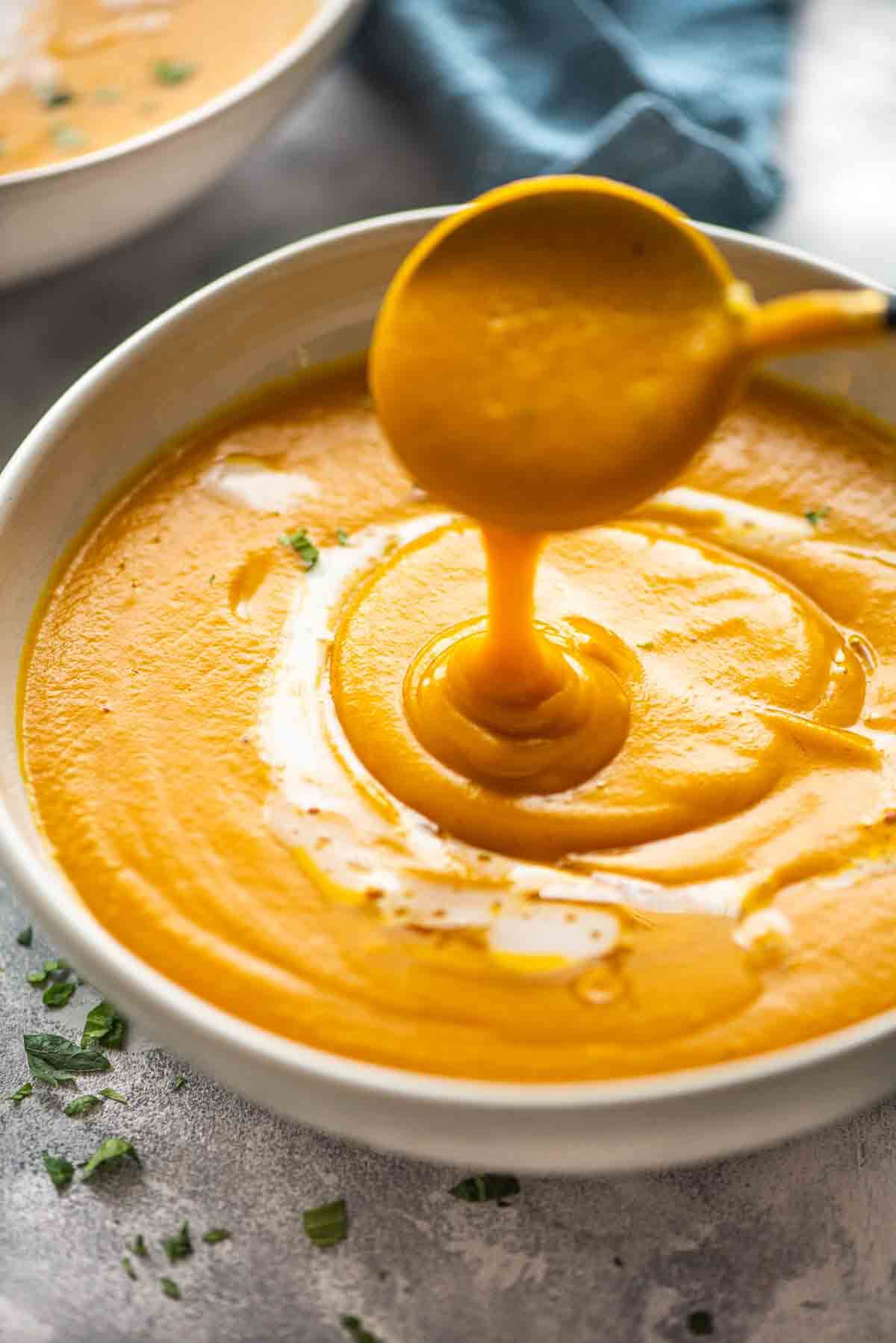 soup spoon pouring out pumpkin soup in a bowl