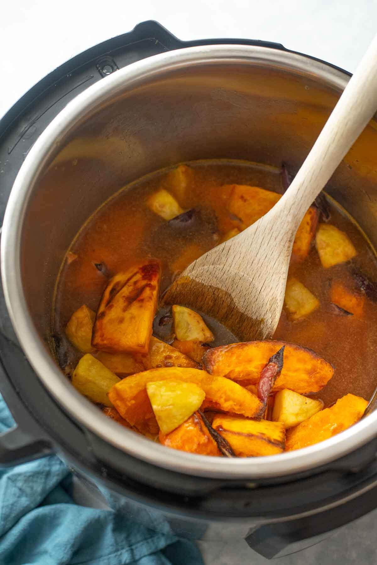 roasted veggies and stock in an instant pot with a spatula