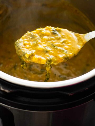 ladle holding palak dal over an instant pot