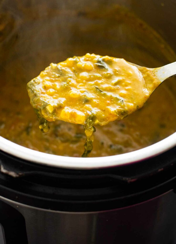 ladle holding palak dal over an instant pot 