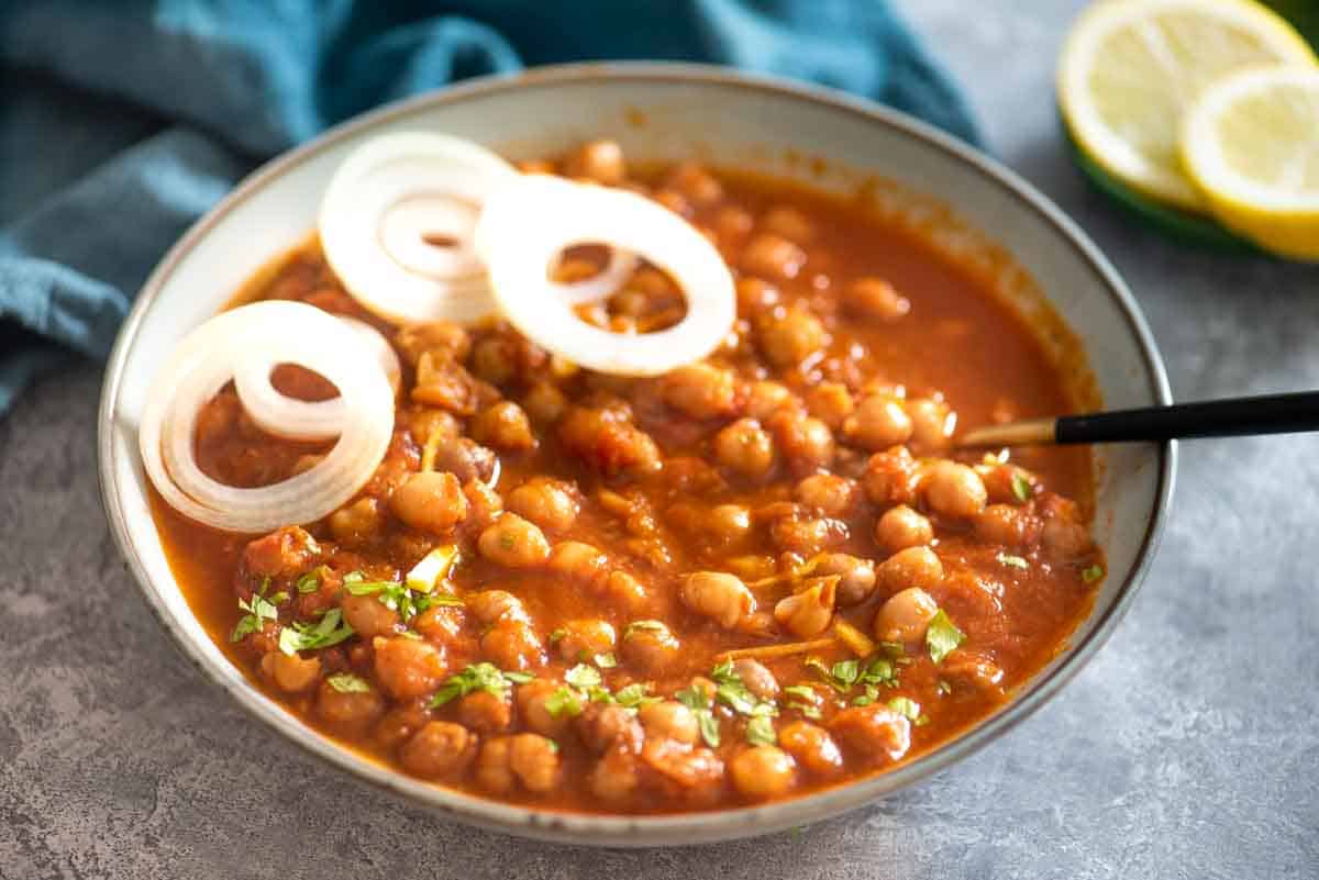 bowl of chole or chickpea curry served with onions and cilantro garnish