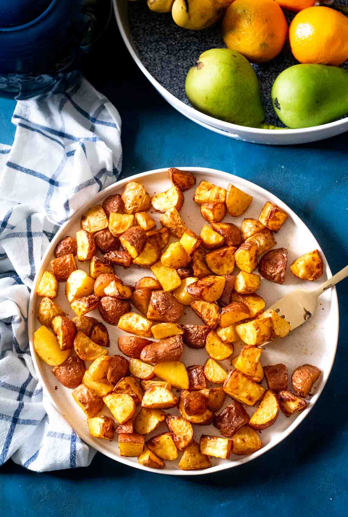 crispy golden brown potatoes on a plate next to fruit