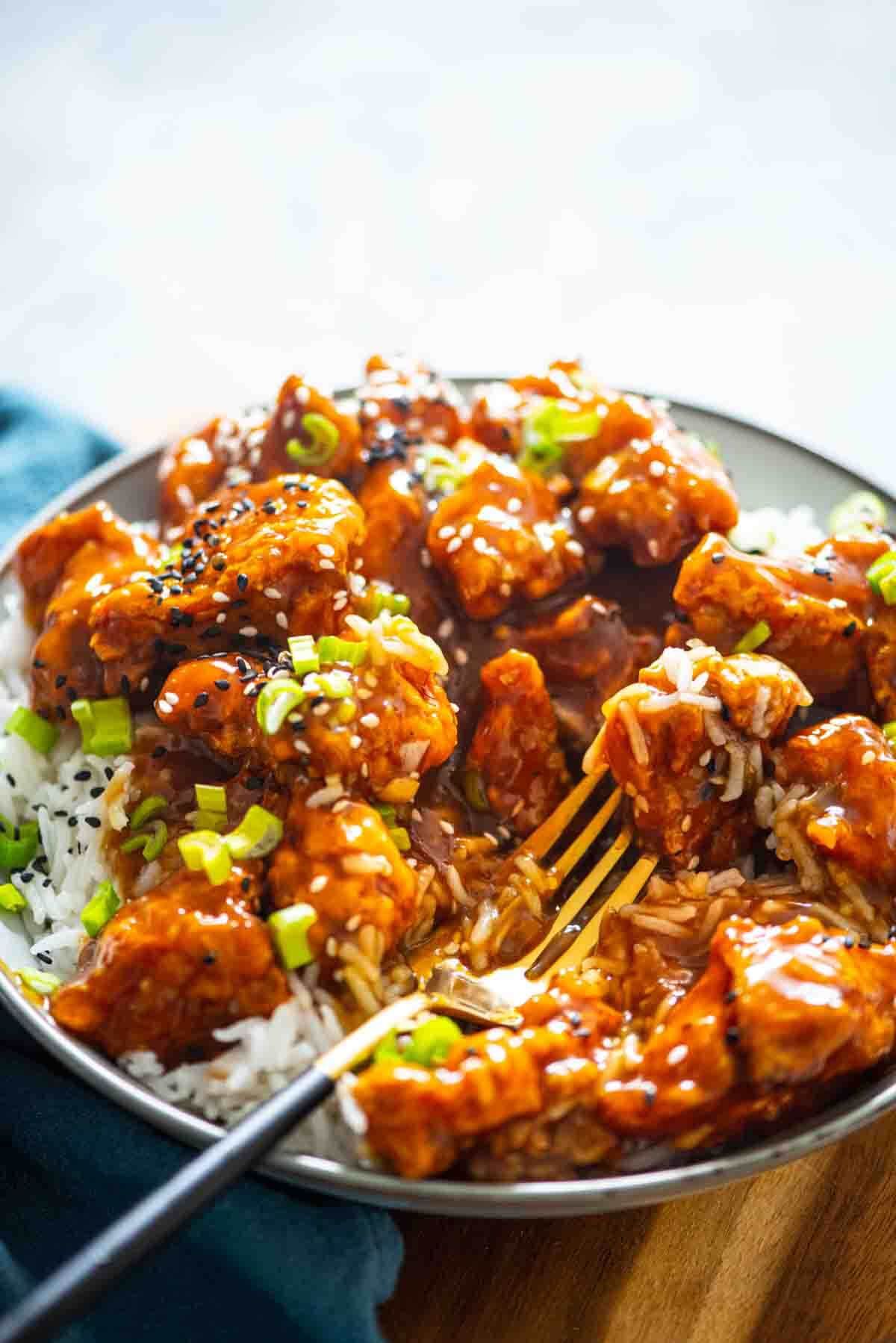 bowl of rice with orange chicken and fork