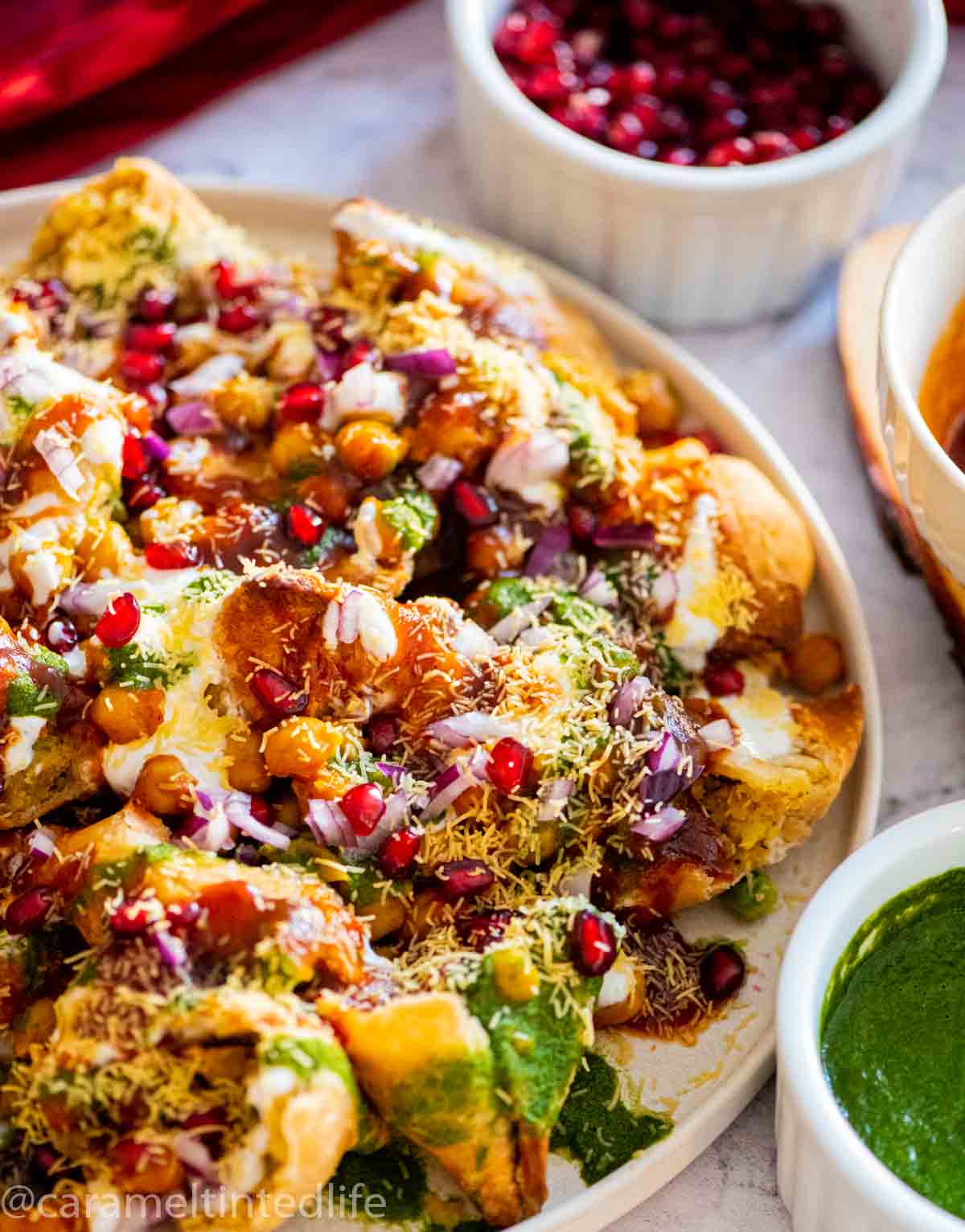 plate with broken samosas and chutney and chaat garnishes