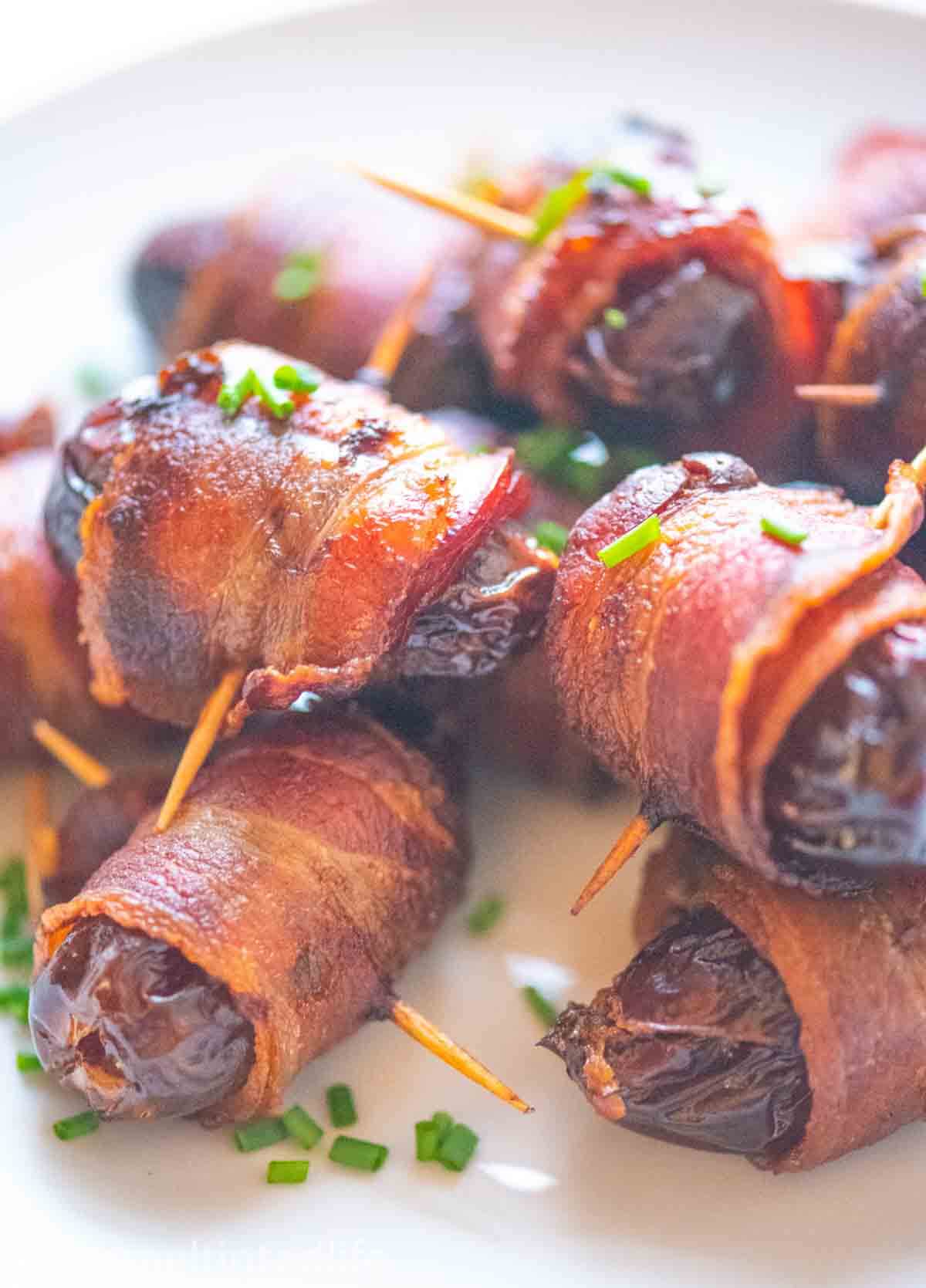 close up of bacon srapped dates with chive garnish 