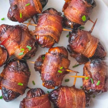 bacon wrapped dates on a white plate