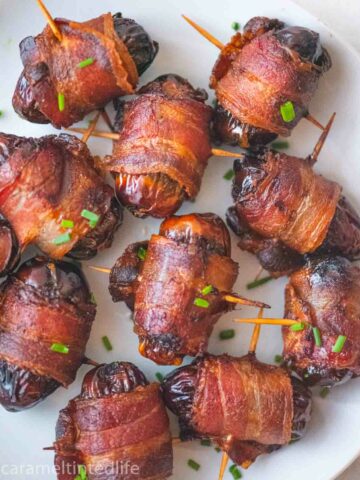 bacon wrapped dates on a white plate