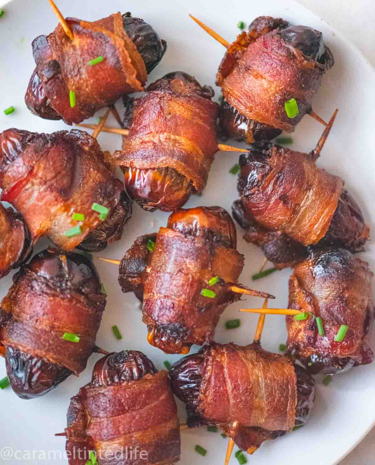 bacon wrapped dates on a white plate