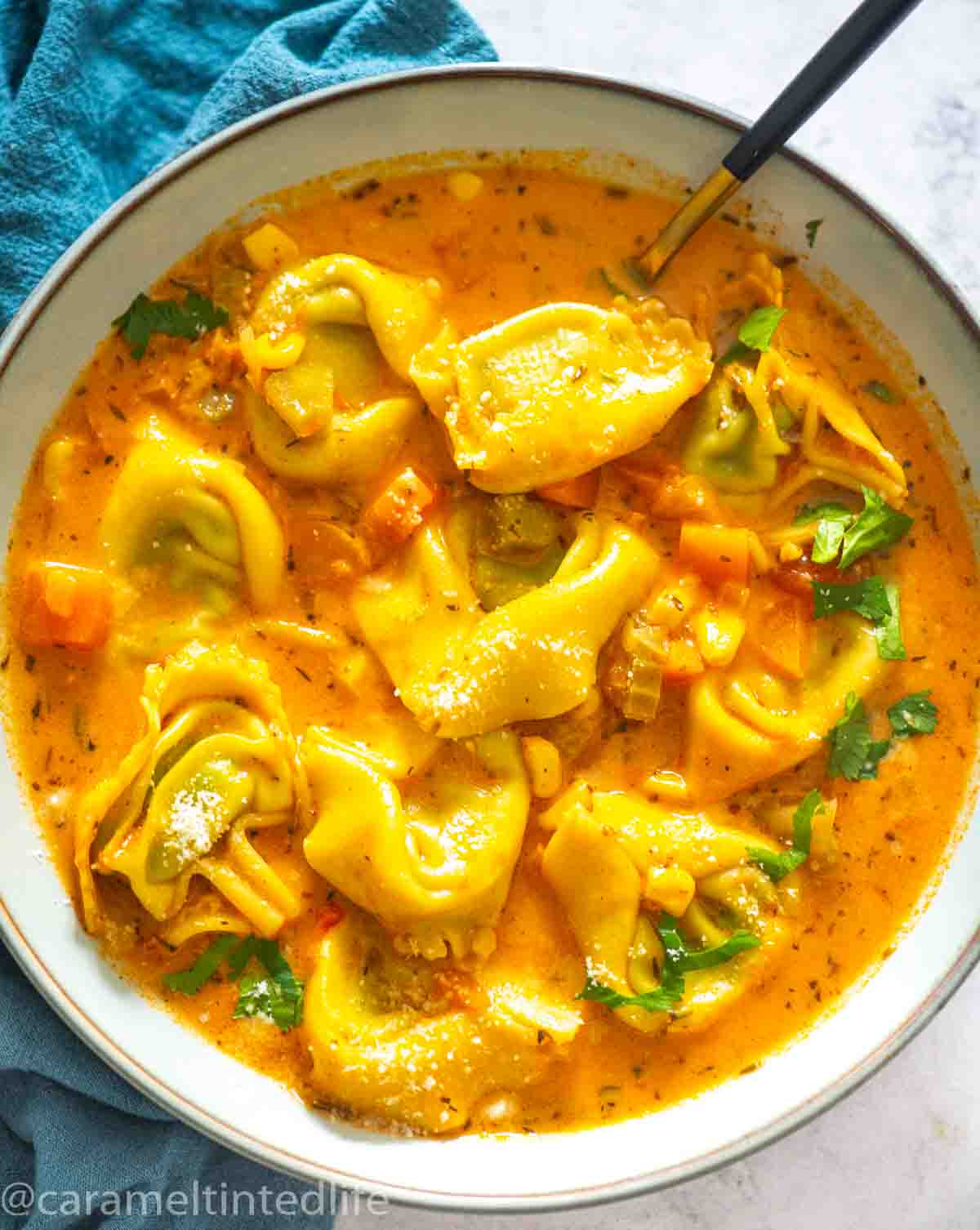 bowl of tortellini soup with a spoon