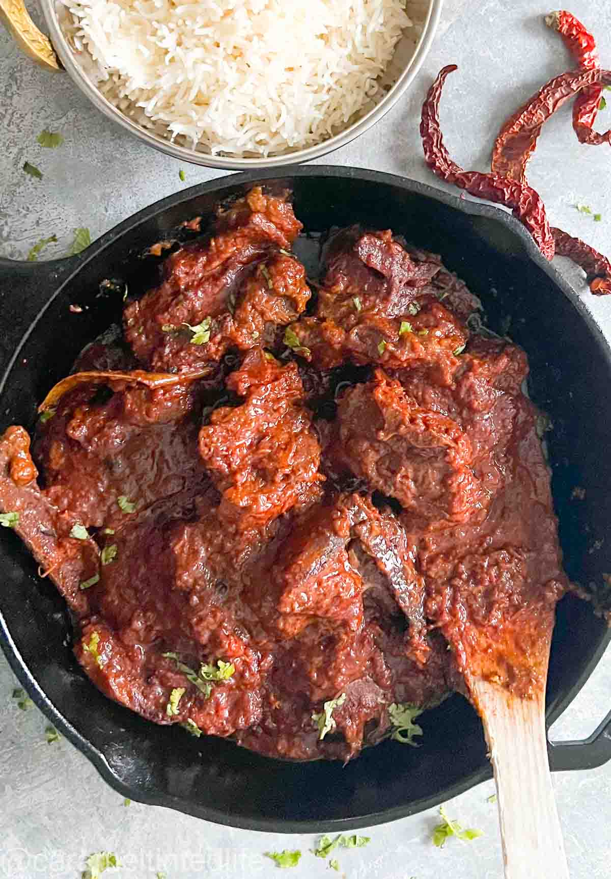 red meat curry in black pan with spatula