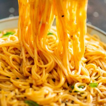 chopsticks holding noodles over a bowl