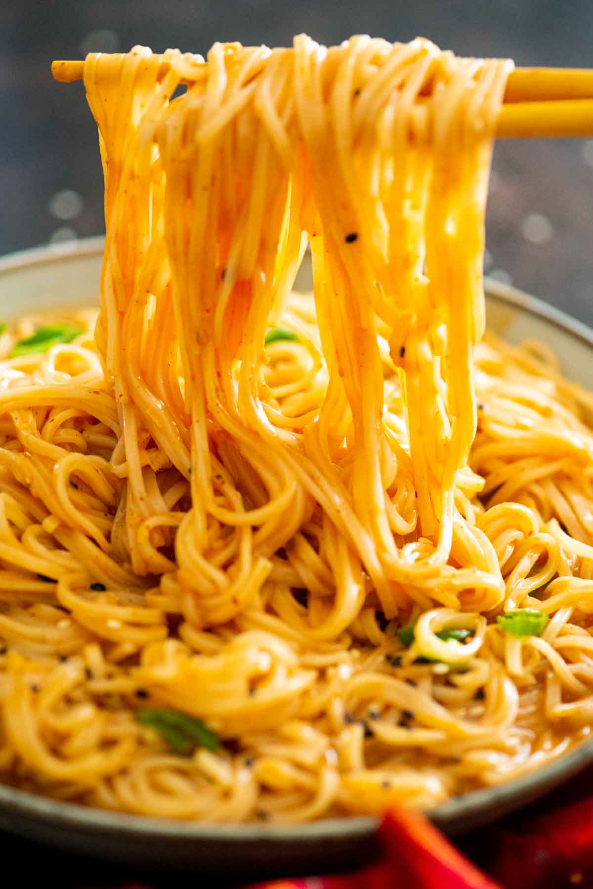 chopsticks holding noodles over a bowl