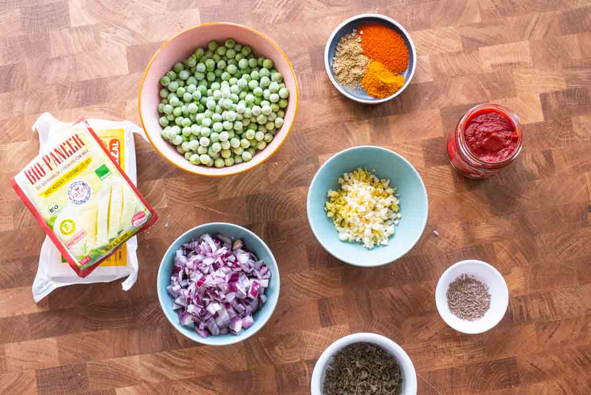 ingredients used to make matar paneer on a wooden board