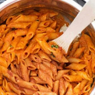 A Instant Pot with cooked pasta, with a wooden spatula